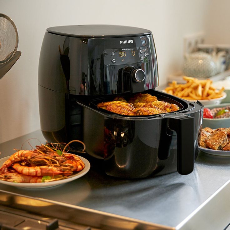 Open air-fryer on a table with air-fried food on plates